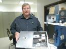 ARRL Lab Test Engineer Bob Allison, WB1GCM, holds a newly functional OSCAR I. The Project OSCAR team built three satellites: One of the satellites went up into space in 1961, one is on display at the Smithsonian Air and Space Museum in Washington, DC and the other was until recently sitting in a display case on the first floor of the ARRL Headquarters building in Newington. The satellite is shown with its cover open tot he left, making the bird appear twice as large as it actually is. [S. Khrystyne Keane, K1SFA, Photo]